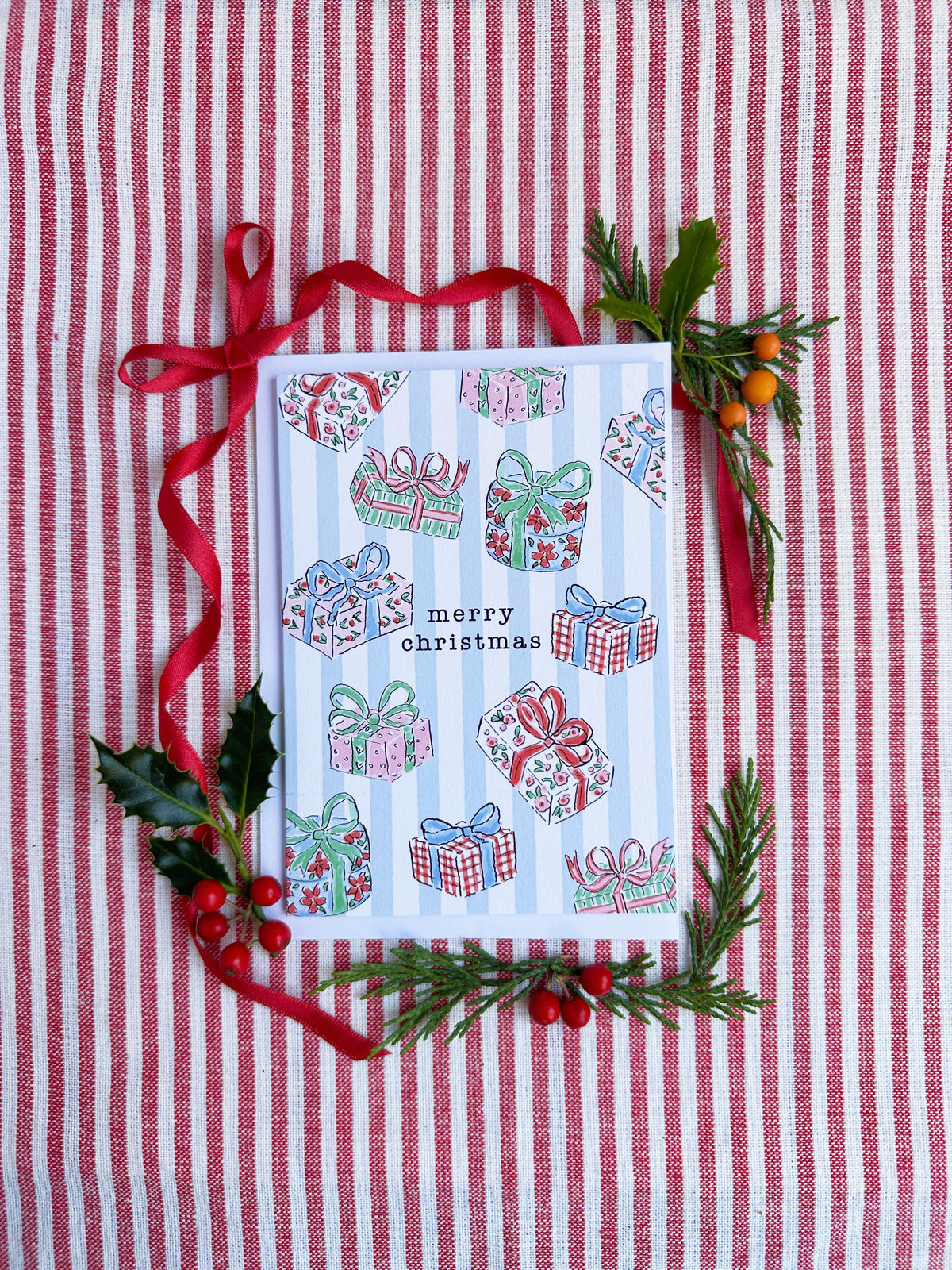 christmas card of illustrated christmas gifts surrounded by bows and evergreens on a red and white striped backdrop