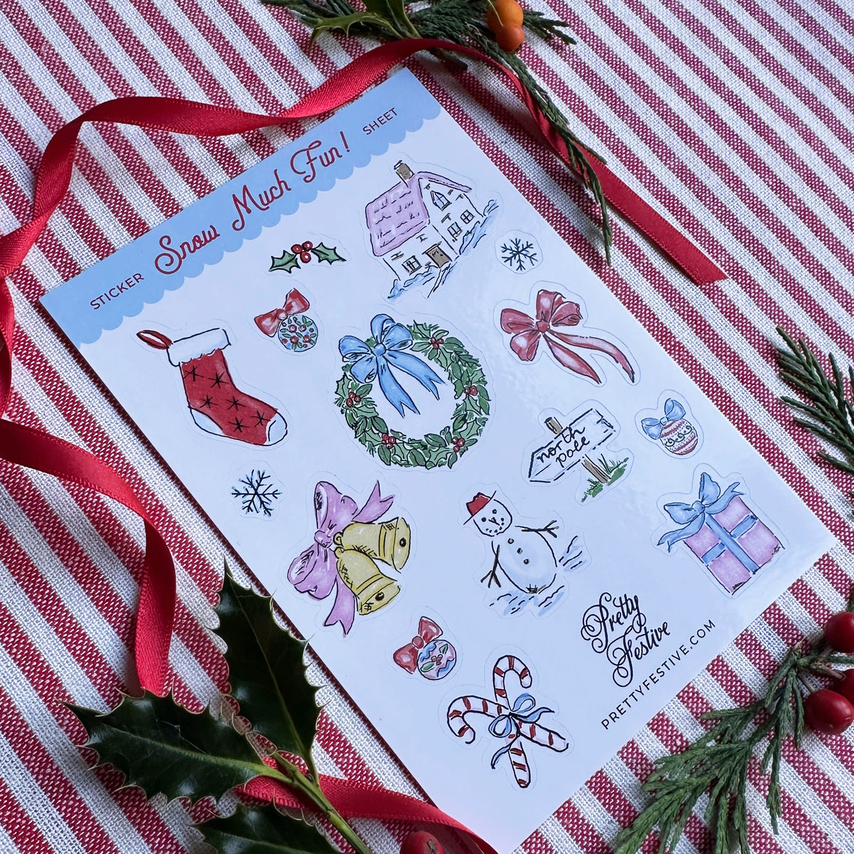 A6 Sticker Sheet caption Snow Much Fun featuring several Christmas themed illustrations. Background is red and white striped fabric, red ribbon and foliage and berries