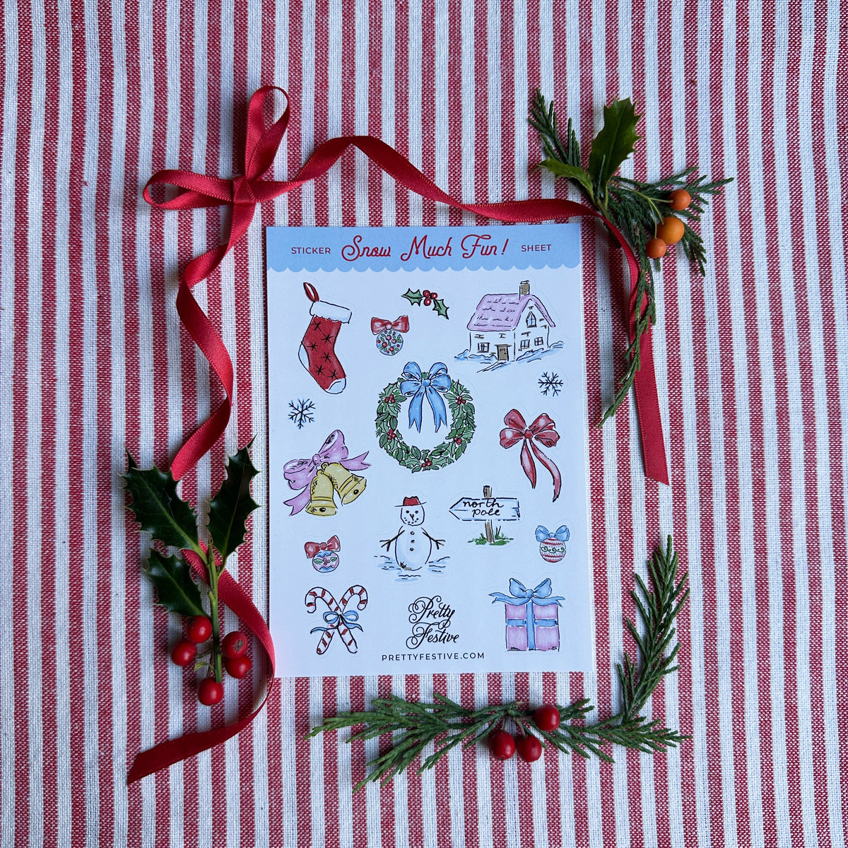 A6 Sticker Sheet caption Snow Much Fun featuring several Christmas themed illustrations. Background is red and white striped fabric, red ribbon and foliage and berries